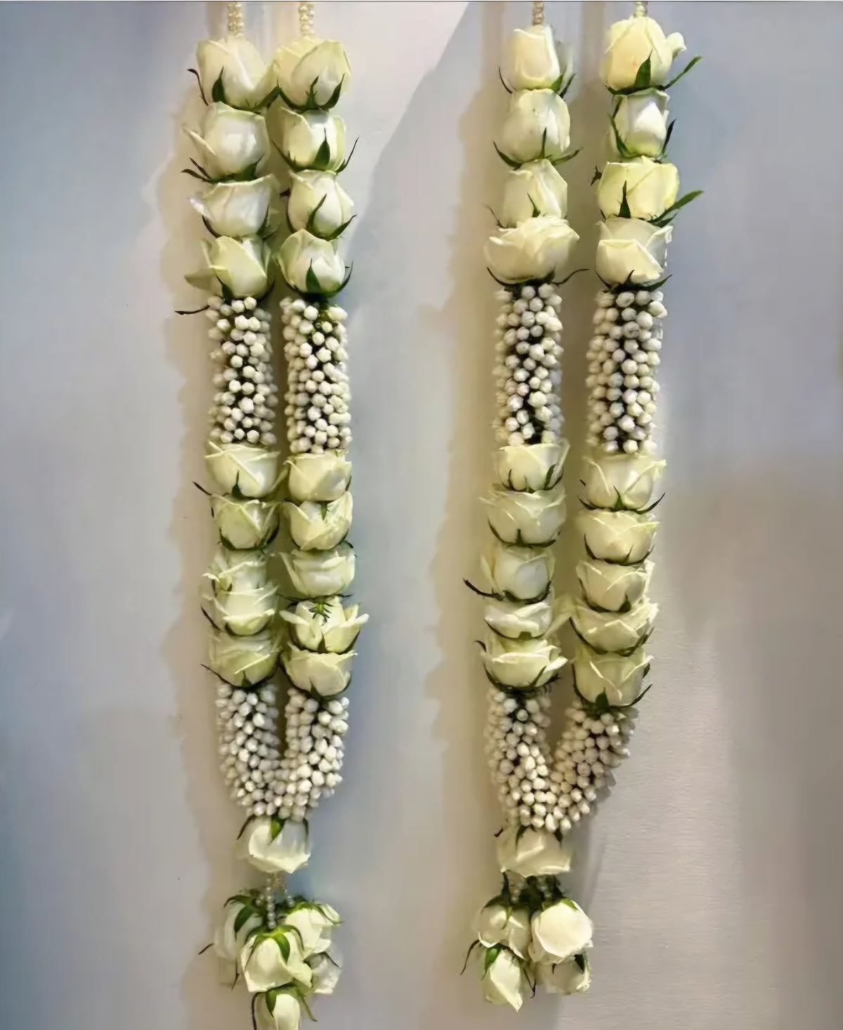 Ivory white rose floral varmala pair for bride and groom with clustered white floral accents and decorative hanging ends