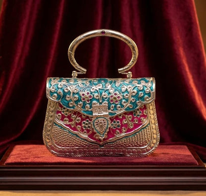 Close-up of blue and pink Meenakari floral detailing and Kundan embellishments on an antique brass clutch