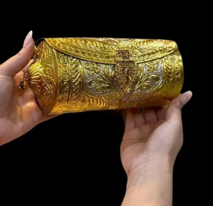 Double-tone brass gold ethnic clutch styled for a wedding occasion