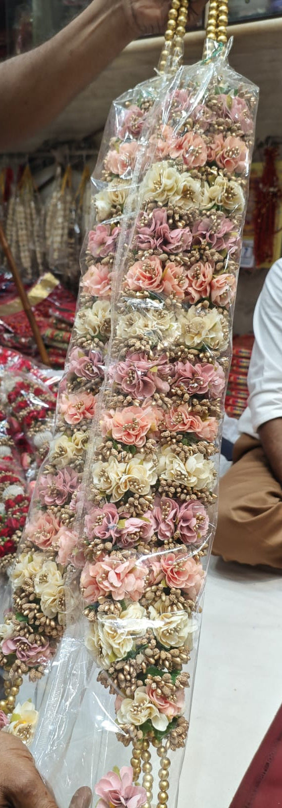 Close-up of handcrafted wedding jaimala flowers in pink and ivory with golden bead detailing