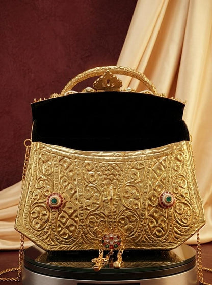Gold Rajwadi bridal purse featuring intricate traditional embossed patterns, colourful Kundan-style stonework, an ornamental handle and a long sling chain.