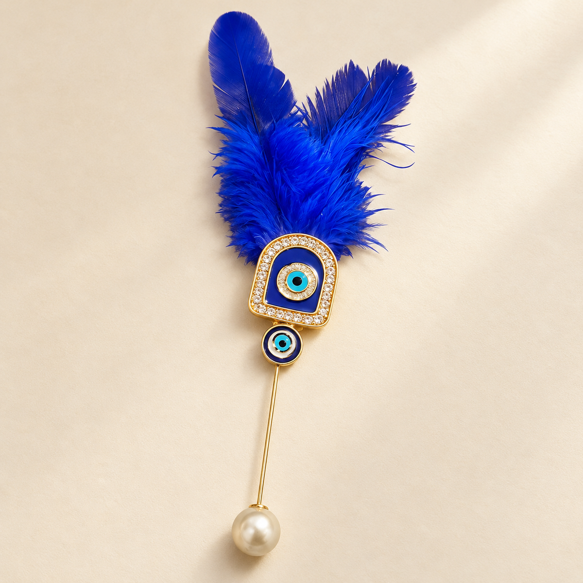 Close-up of a golden evil eye brooch featuring royal blue feathers, crystal embellishments and a pearl drop for traditional wedding guest welcomes.