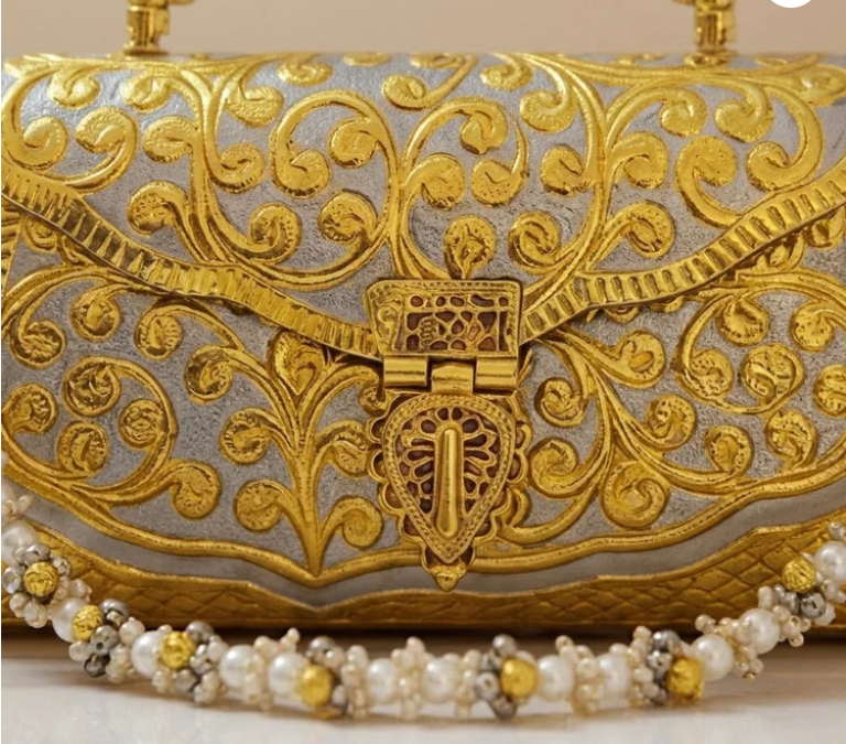 Close-up of the gold-tone Meenakari purse showing intricate floral artwork and pearl embellishments