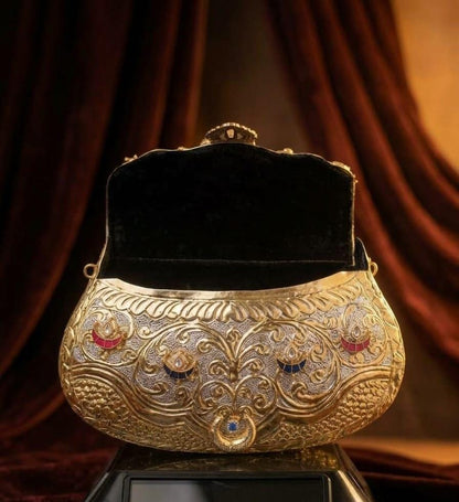 Royal antique gold metal clutch with an ornate floral embossed design, multicolour stone embellishments and a circular top handle for weddings and festive occasions.