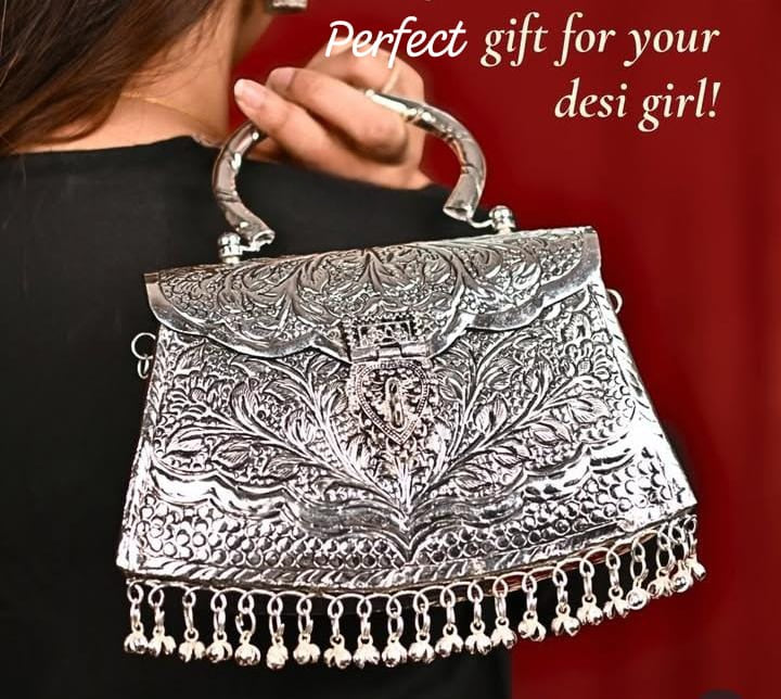 Close-up of engraved silver brass clutch with traditional ghungroo detailing